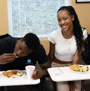 student eating and student smiling at camera